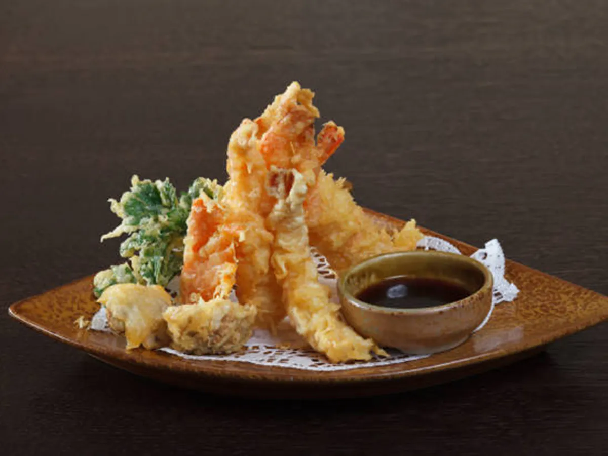 Crispy shrimp tempura with soy dipping sauce on ceramic plate