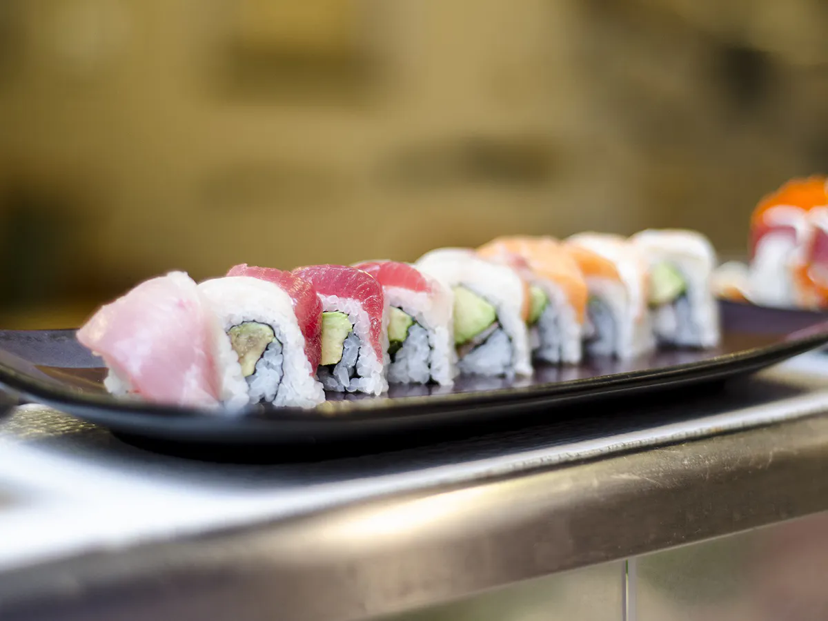 Fresh tuna salmon avocado sushi rolls on dark plate